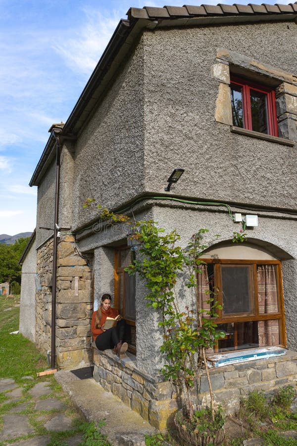 Woman sitting and reading at the entrance of a country house, vertical. Woman sitting and reading at the entrance of a country house, vertical