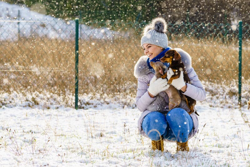 Kvinna som spelar med hundkapplöpning under vinter fotografering för bildbyråer Kvinna som spelar med hundkapplöpning under vinter fotografering för bildbyråer