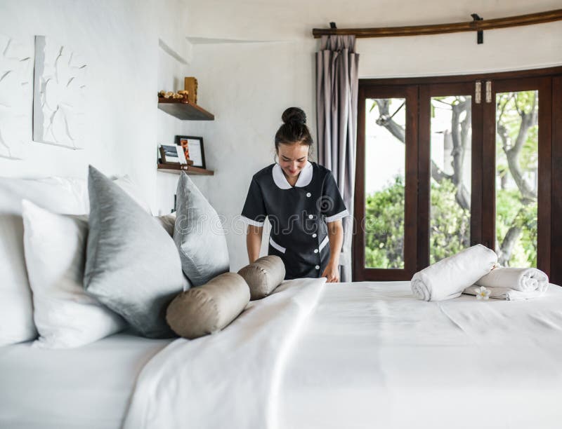 Kvinna som ställer in sängen i hotellrummet arkivbilder Kvinna som ställer in sängen i hotellrummet arkivbilder