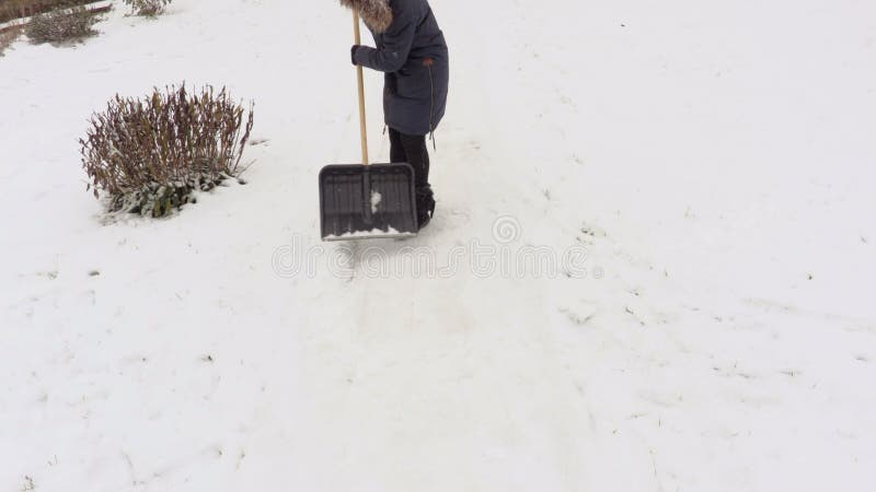 Kvinna som tar bort snö från den dolda banan för snö