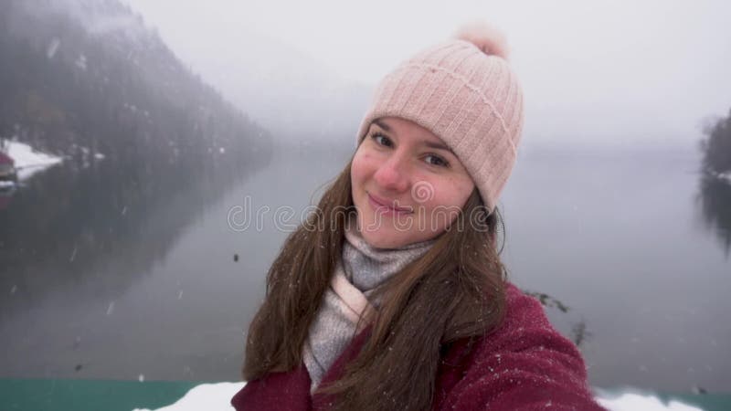 Kvinna som tar selfie och ler på Ritsa sjön i Abchazien Sn?ig dag i vinter