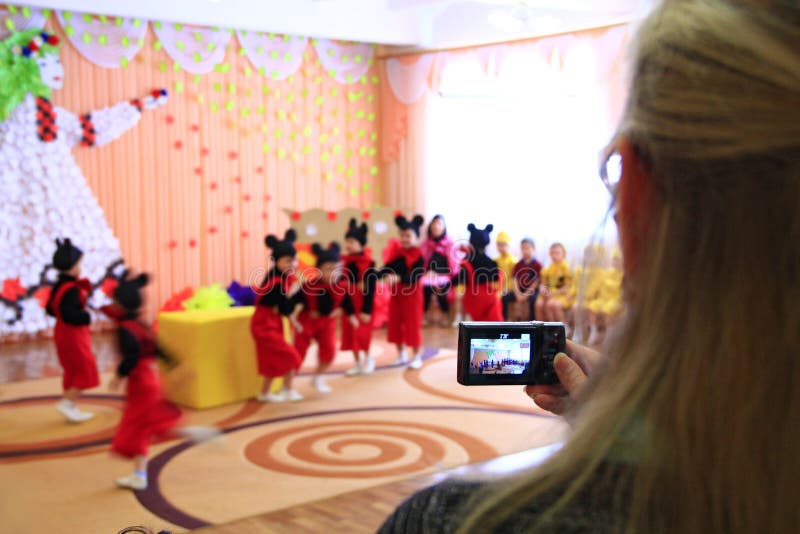 Kvinna som tar videoen av barns morgonpartiet Barn på matiné på dagiset royaltyfri foto Kvinna som tar videoen av barns morgonpartiet Barn på matiné på dagiset royaltyfri foto