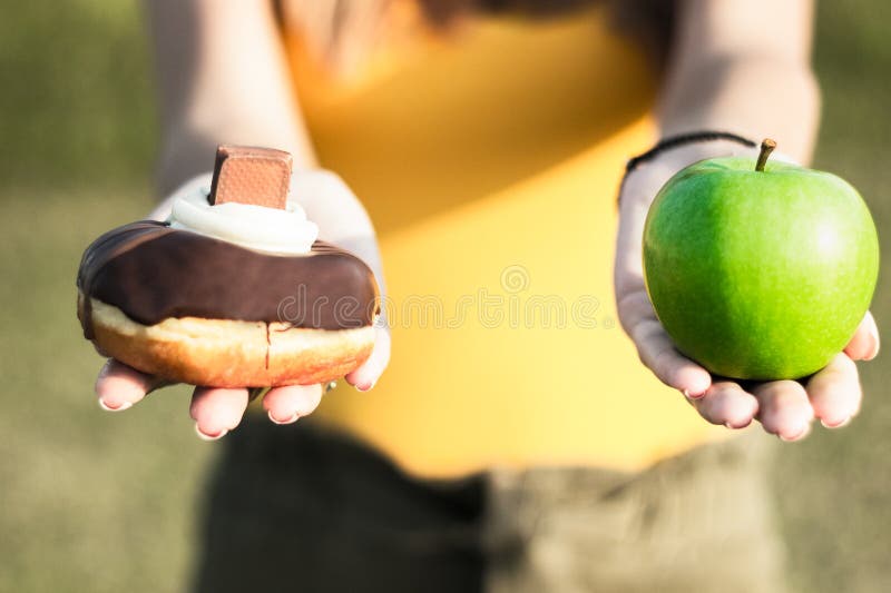 Kvinna som väljer mellan sunda frukter och munken royaltyfri bild Kvinna som väljer mellan sunda frukter och munken royaltyfri bild