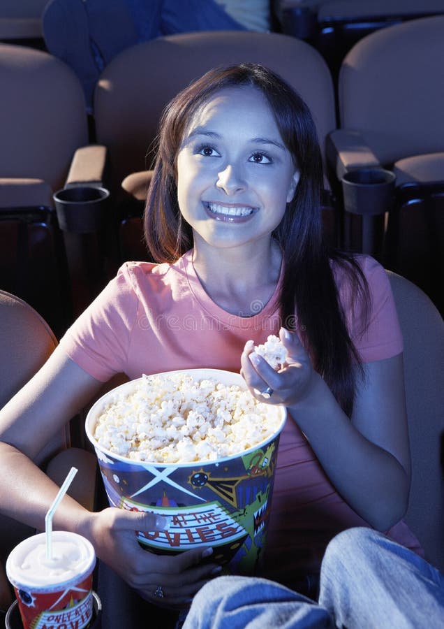 Kvinna som äter popcorn, medan hålla ögonen på film i teater