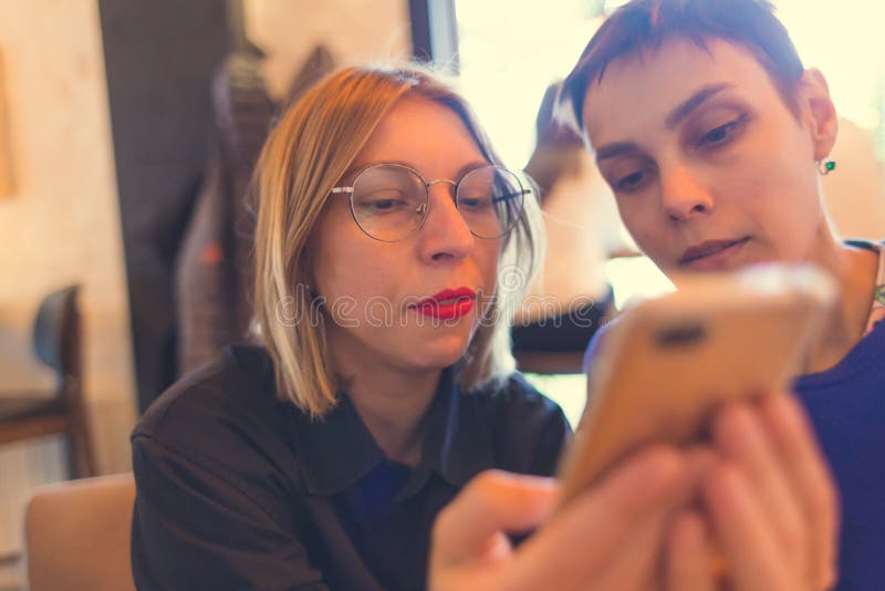 Kvinna visar sin vän en mobiltelefon fotografering för bildbyråer