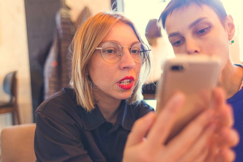Kvinna visar sin vän en mobiltelefon arkivbilder