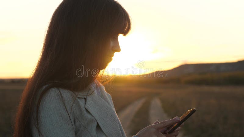 Kvinnabonde som arbetar med en minnestavla i fält i solsken flickans hand skrivar ut ett mobilt meddelande på smartphoneskärmen royaltyfri bild Kvinnabonde som arbetar med en minnestavla i fält i solsken flickans hand skrivar ut ett mobilt meddelande på smartphoneskärmen royaltyfri bild