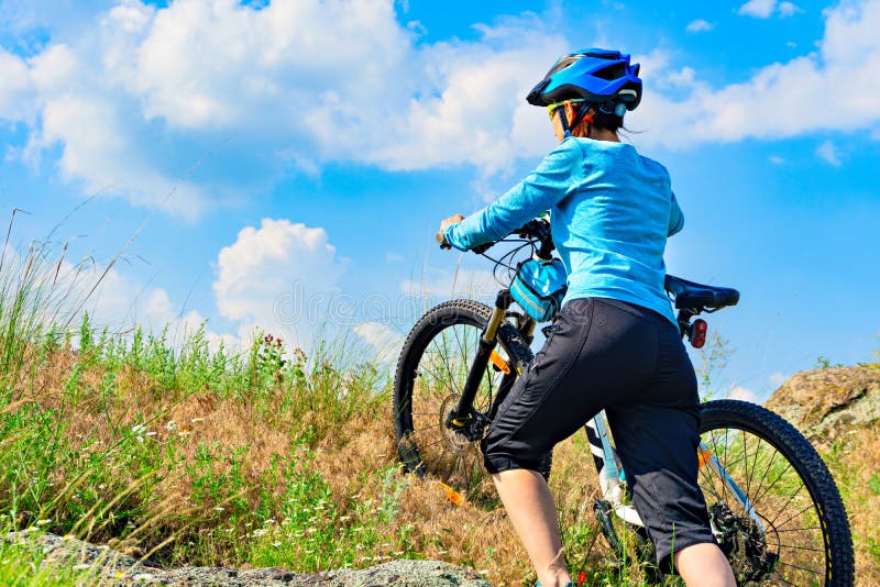 Kvinnacyklist som skjuter hennes cykel upp ett stup fotografering för bildbyråer Kvinnacyklist som skjuter hennes cykel upp ett stup fotografering för bildbyråer