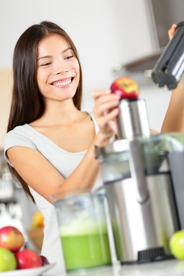 Kvinnadanandeäpple och grönsakfruktsaft på juiceren royaltyfri fotografi