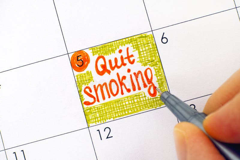 Woman fingers with pen writing reminder Quit Smoking in calendar. Close-up. Woman fingers with pen writing reminder Quit Smoking in calendar. Close-up.