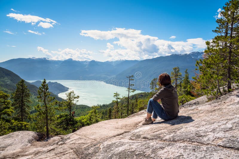 Kvinnafotvandrare som kopplar av på överkanten av ett berg och beundrar det sceniska landskapet royaltyfri bild Kvinnafotvandrare som kopplar av på överkanten av ett berg och beundrar det sceniska landskapet royaltyfri bild