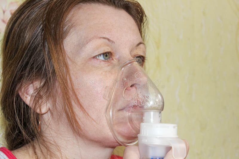 Kvinnan behandlas hemma med en nebulizer. behandling av hosta- virus och infektioner