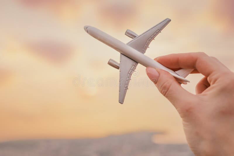 Kvinnan har en flygplansmodell i handen i bakluften under solnedgången. stängningsvy. royaltyfria foton Kvinnan har en flygplansmodell i handen i bakluften under solnedgången. stängningsvy. royaltyfria foton