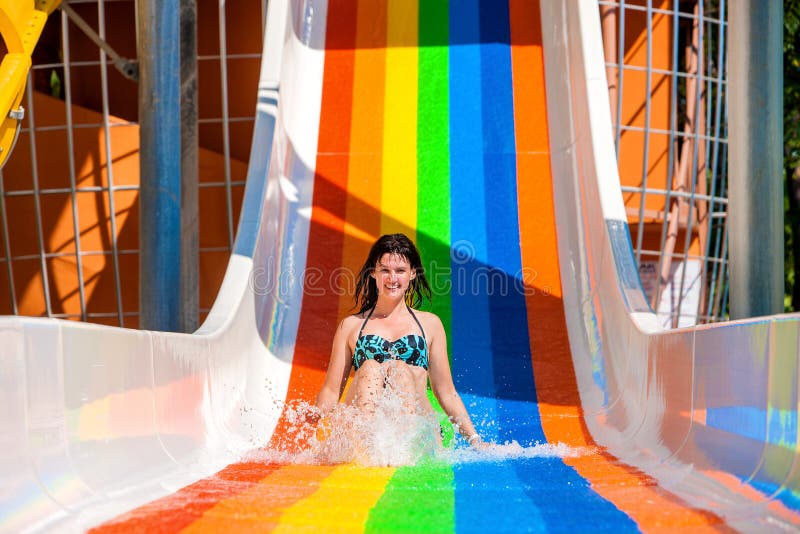 Happy woman in bikini sliding water park. Rainbow color. Happy woman in bikini sliding water park. Rainbow color.