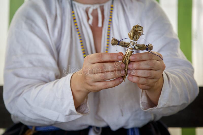 Kvinnan i rysk etnisk kl?der g?r en liten leksak av sugr?r royaltyfri fotografi Kvinnan i rysk etnisk kl?der g?r en liten leksak av sugr?r royaltyfri fotografi