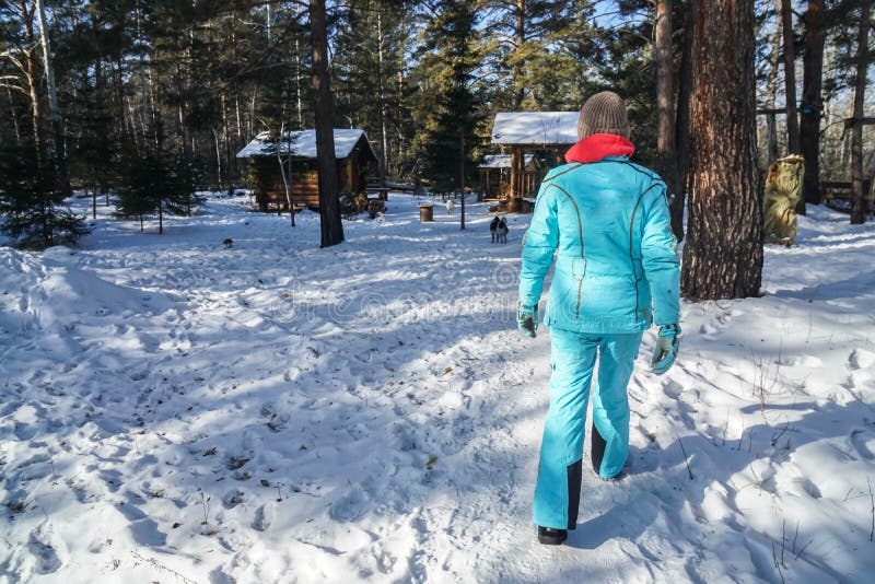 Kvinnan med den stack ullhatten och vinterlaget går på snö som går till träkabinen i skog royaltyfri bild Kvinnan med den stack ullhatten och vinterlaget går på snö som går till träkabinen i skog royaltyfri bild