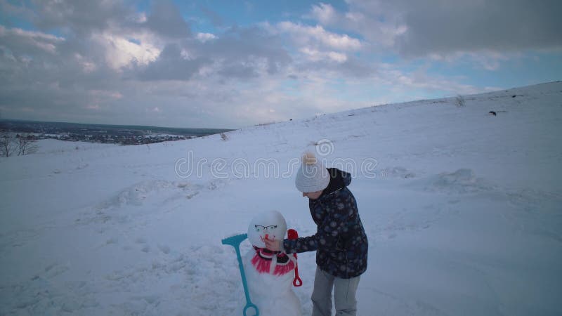 Kvinnan och barnet hugger tillsammans en sn?gubbe p? kullen