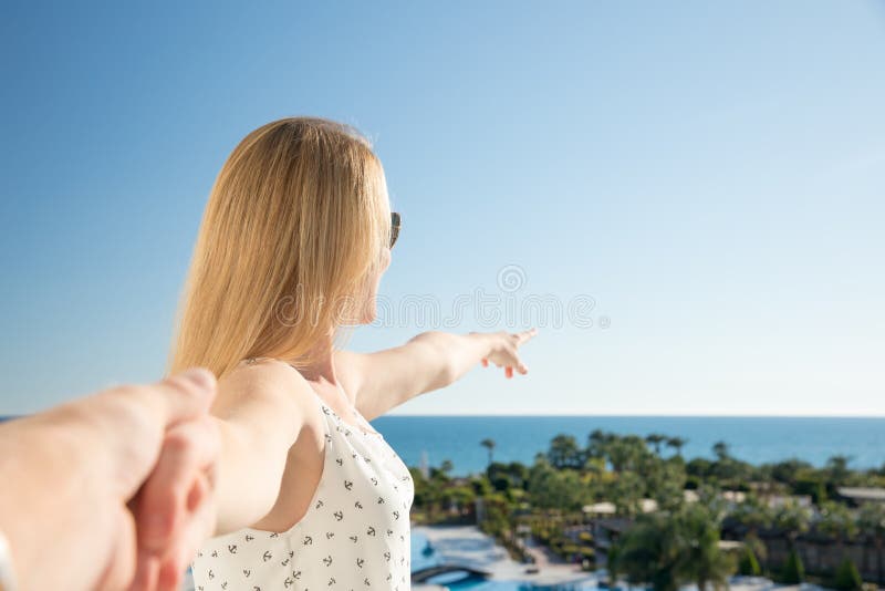 Kvinnan pekar med hennes finger till havet från ett balkony i sommarferie arkivbild Kvinnan pekar med hennes finger till havet från ett balkony i sommarferie arkivbild