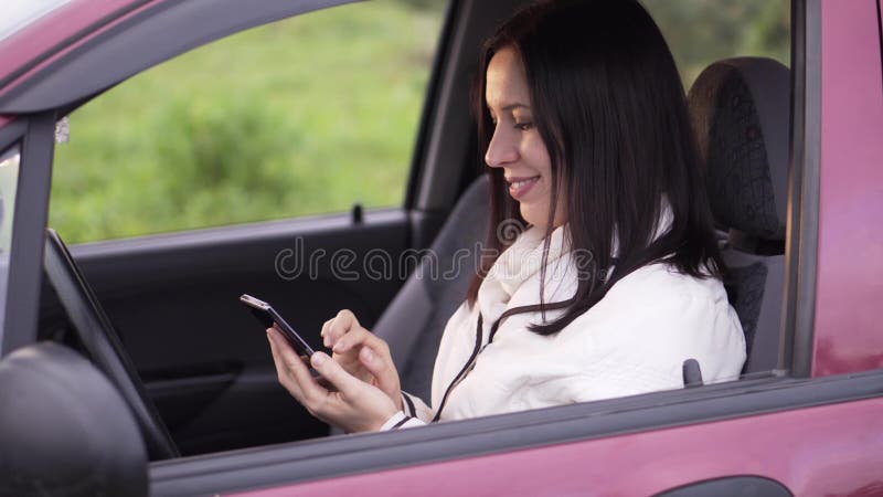 Kvinnan skriver ett meddelande på ett smartphonesammanträde i bilen