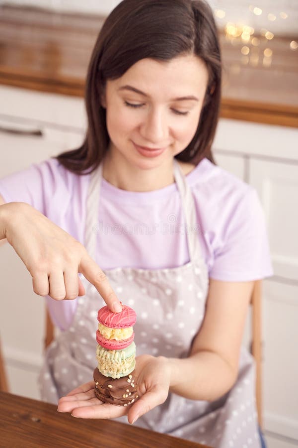 Kvinnan som balanserar vibrerande, färgade makaroner i hemkök med en polka punkt arkivbild