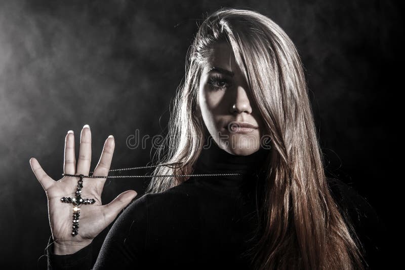 Young woman holding a cross on her palm in a smoke. Young woman holding a cross on her palm in a smoke