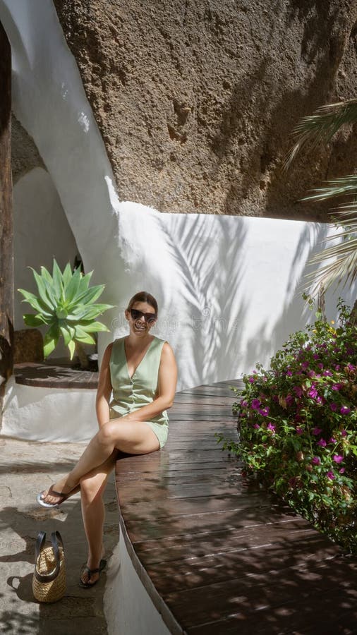 Kvinnan som sitter utomhus i lagomar lanzarote med solglasögon omgivna av grön och unik bergsarkitektur arkivbilder