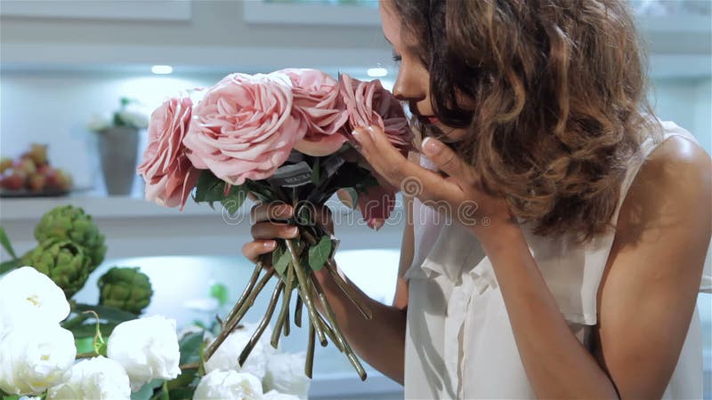 Kvinnan tar en bukett av rosa rosor på blomsterhandeln