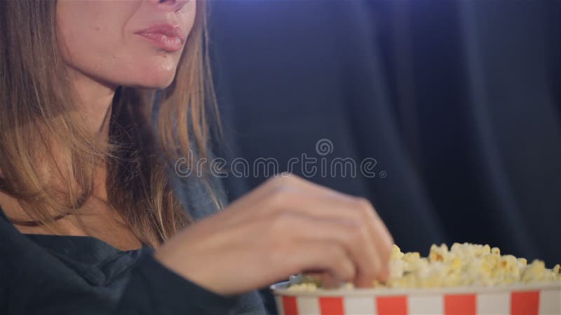 Kvinnan tar flingor av popcorn från hinken