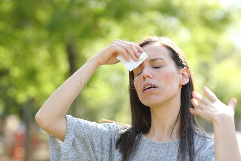 Stressed woman drying sweat using a wipe in a warm summer day in a park. Stressed woman drying sweat using a wipe in a warm summer day in a park