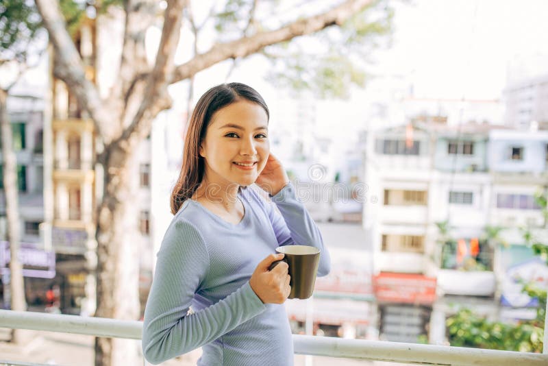 Kvinnan tycker om hennes kaffe p? balkongen fotografering för bildbyråer Kvinnan tycker om hennes kaffe p? balkongen fotografering för bildbyråer