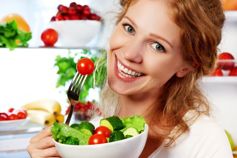Kvinnan äter vegetarisk sallad för den sunda matgrönsaken om refrige royaltyfri bild