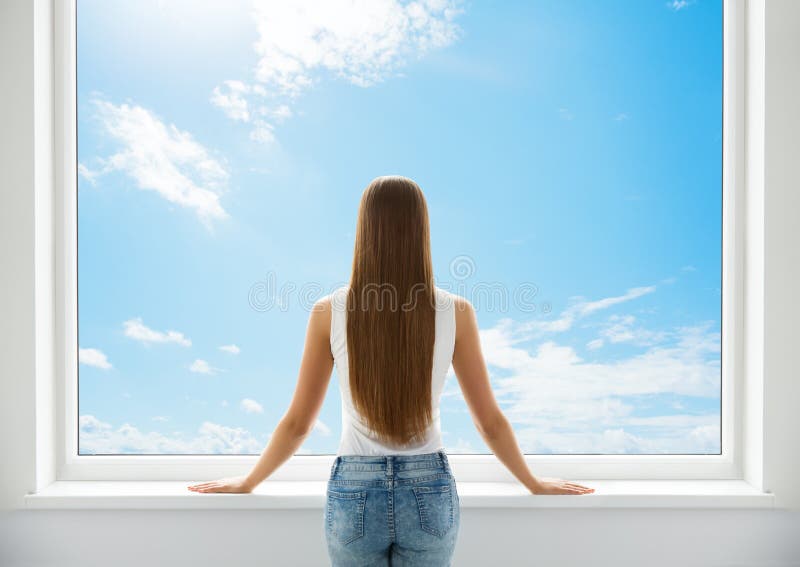Kvinnans bakre vy som tittar på fönstret. Unga flickor på baksidan av silhuette ser framåt och tänker. morgonväckare. himmel arkivbilder