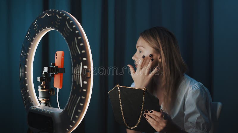 Kvinnans skönhetsbloggare använder kosmetikaprodukter på ansiktet framför ringljus