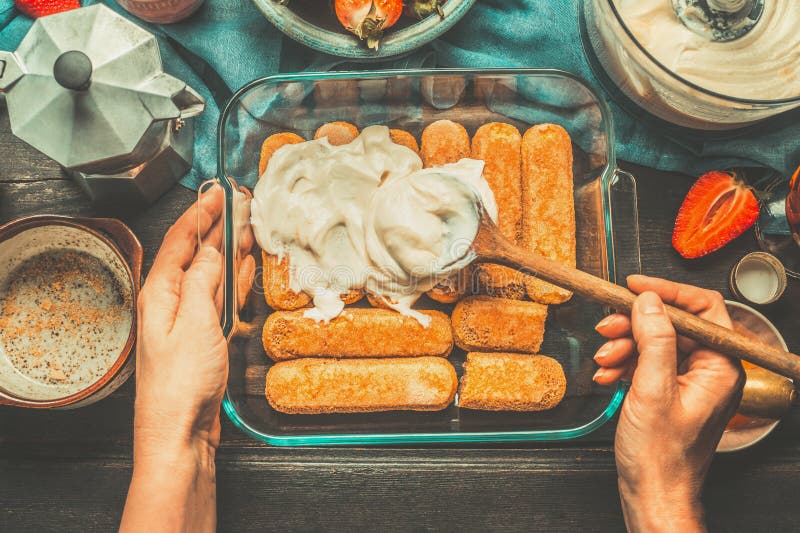 Kvinnas kvinnliga händer suddiga kräm på kakan på mörk lantlig träbakgrund, bästa sikt Italienskt matbegrepp arkivfoto Kvinnas kvinnliga händer suddiga kräm på kakan på mörk lantlig träbakgrund, bästa sikt Italienskt matbegrepp arkivfoto