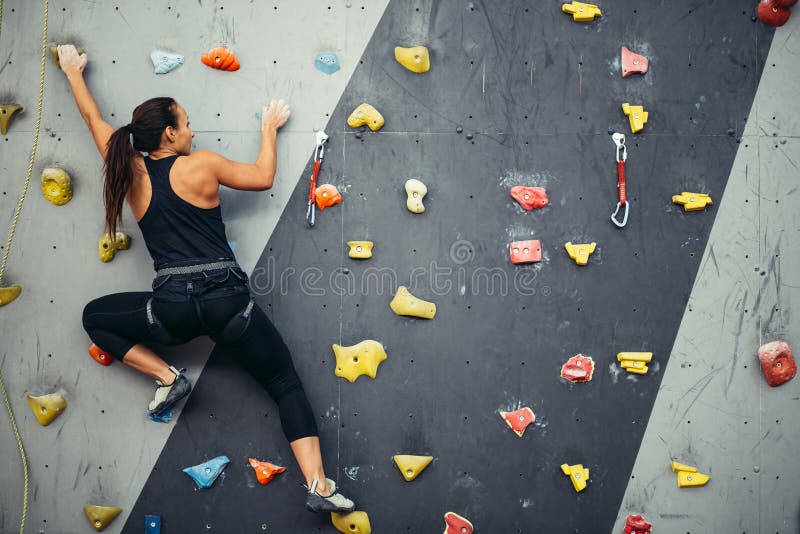 Kvinnaövning vaggar klättring på den konstgjorda väggen inomhus Aktiv livsstil och bouldering begrepp royaltyfri fotografi