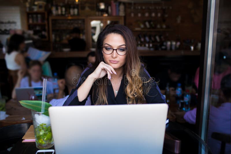 Kvinnlig bloggerläsningartikel i internet via anteckningsboken under fri tid i restaurang fotografering för bildbyråer Kvinnlig bloggerläsningartikel i internet via anteckningsboken under fri tid i restaurang fotografering för bildbyråer