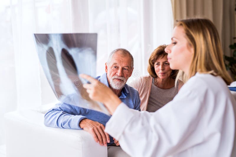 Kvinnlig doktor med röntgenstrålen som talar till ett högt par royaltyfria bilder Kvinnlig doktor med röntgenstrålen som talar till ett högt par royaltyfria bilder