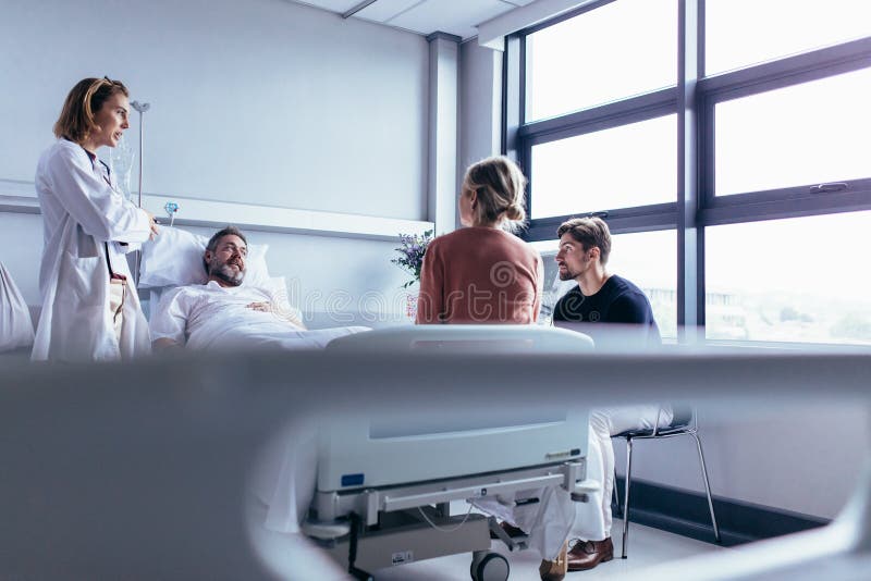 Kvinnlig doktor som besöker patienten i sjukhusrum royaltyfri fotografi