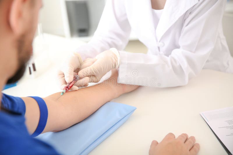 Kvinnlig doktor som drar en blodprövkopia av den manliga patienten i klinik royaltyfria bilder Kvinnlig doktor som drar en blodprövkopia av den manliga patienten i klinik royaltyfria bilder