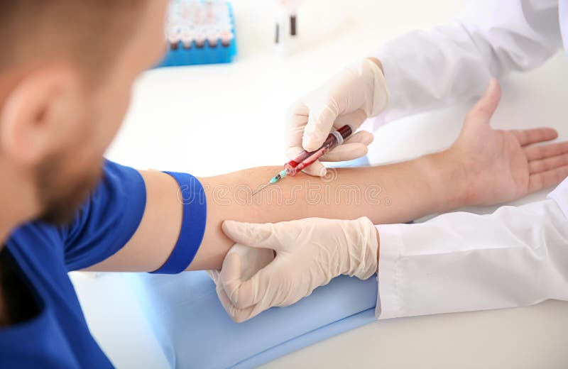 Kvinnlig doktor som drar en blodprövkopia av den manliga patienten i klinik arkivfoton Kvinnlig doktor som drar en blodprövkopia av den manliga patienten i klinik arkivfoton