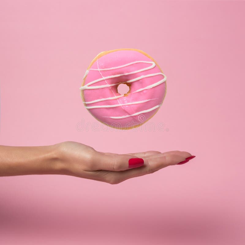 Kvinnlig hand med den läckra munken för flyg på rosa bakgrund arkivbild