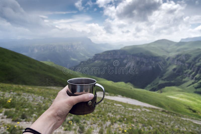 Kvinnlig hand med en kopp te på en bakgrund av berg royaltyfri fotografi Kvinnlig hand med en kopp te på en bakgrund av berg royaltyfri fotografi