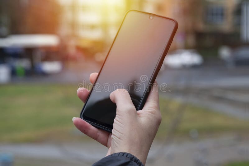 Kvinnlig hand som håller smarttelefon framför svart bakgrund royaltyfri bild Kvinnlig hand som håller smarttelefon framför svart bakgrund royaltyfri bild