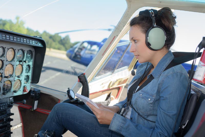 Kvinnlig helikopterpilot som läser handboken, medan sitta i cockpit fotografering för bildbyråer Kvinnlig helikopterpilot som läser handboken, medan sitta i cockpit fotografering för bildbyråer