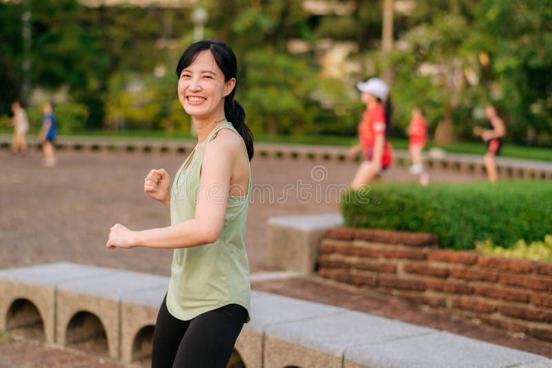 Kvinnlig joggare. en ung kvinna med grön sportkläder och flygplansdans i parken och med friska utomhusaktiviteter. duglighet royaltyfri fotografi