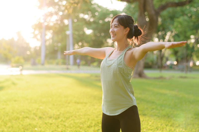 Kvinnlig joggare. lämplig ung asiatisk kvinna med grönt sportkläder som spänner muskeln i parken innan hon går och njuter av en fr royaltyfria foton