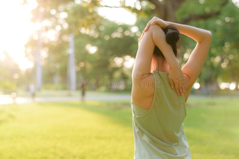 Kvinnlig joggare. lämplig ung asiatisk kvinna med grönt sportkläder som spänner muskeln i parken innan hon går och njuter av en fr royaltyfri bild