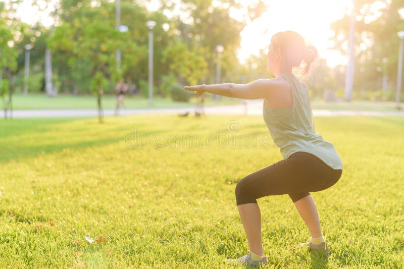 Kvinnlig joggare. lämplig ung asiatisk kvinna med grönt sportkläder som spänner muskeln i parken innan hon går och njuter av en fr royaltyfri bild