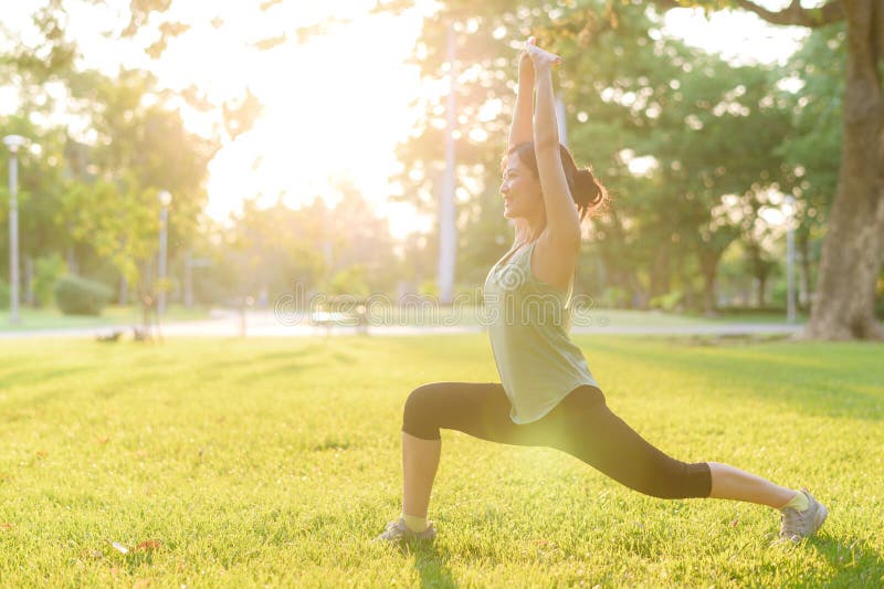 Kvinnlig joggare. lämplig ung asiatisk kvinna med grönt sportkläder som spänner muskeln i parken innan hon går och njuter av en fr arkivbild