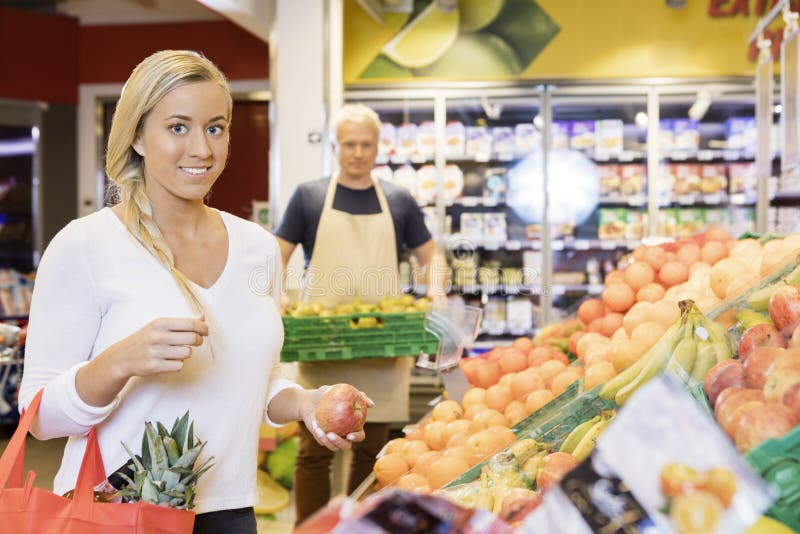 Kvinnlig kund som rymmer Apple i supermarket royaltyfria bilder Kvinnlig kund som rymmer Apple i supermarket royaltyfria bilder